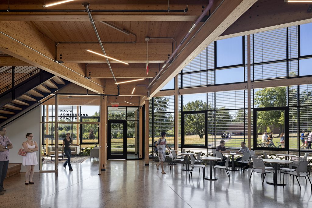Robert bensonkerncenter22 | trim tab Open lobby with exposed wooden beams large glass windows and people standing and sitting near the entrance