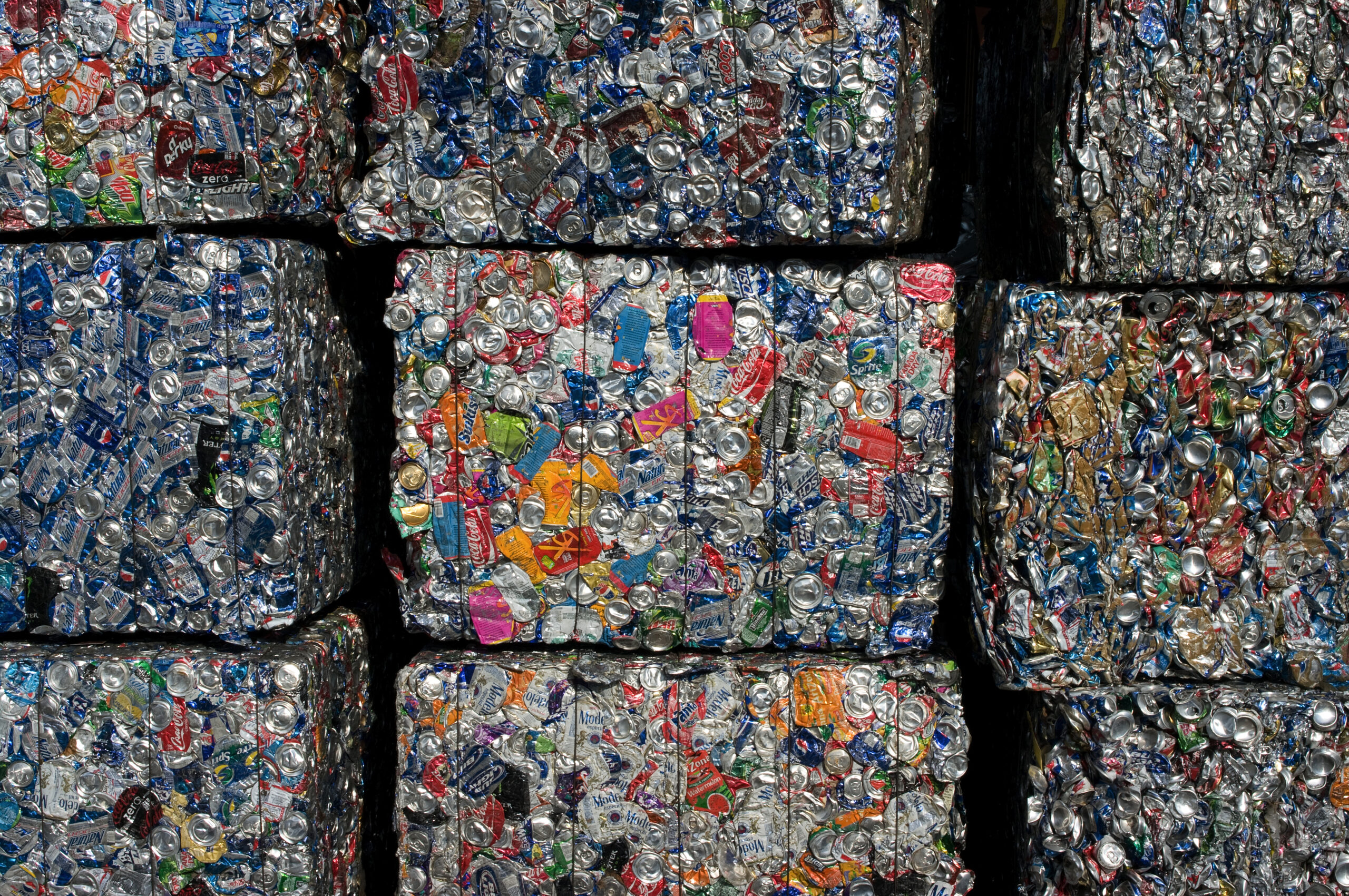 Crushed aluminum beverage cans tightly packed into large rectangular bales for recycling